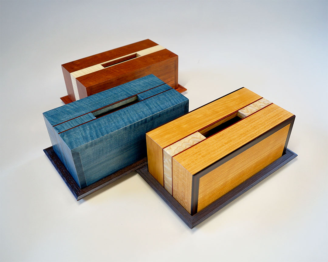 異なる色の木材で作られた3つの手作り木製ティッシュボックス、茶色、青、黄色の美しい木目が特徴的