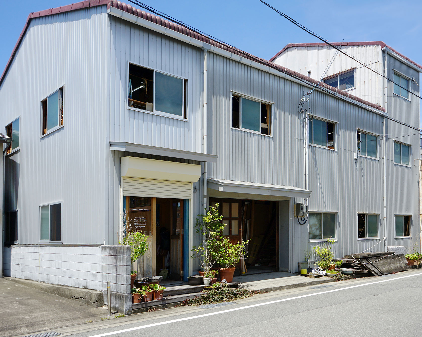 富永ジョイナーの工場外観、グレーの波板壁面に青い扉が特徴的な建物