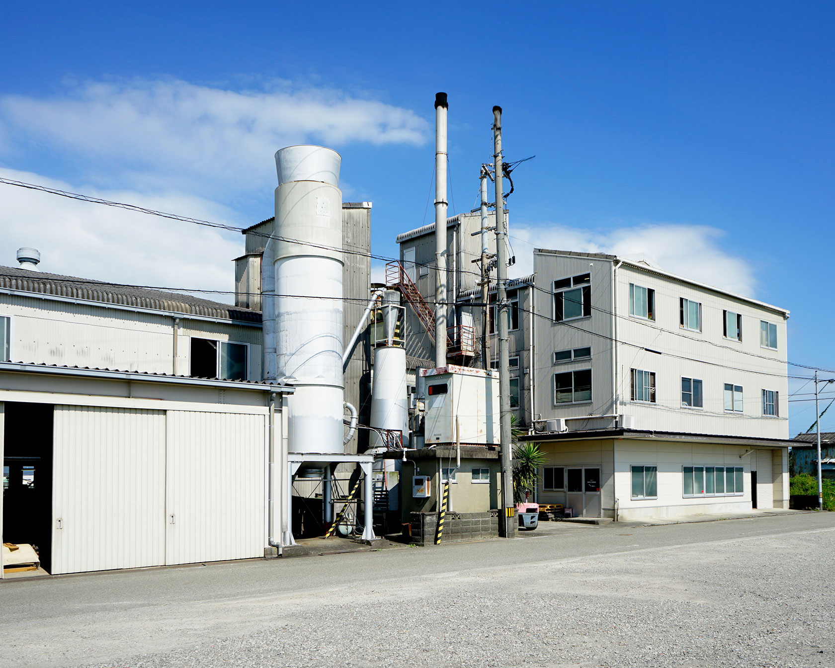 秋月木工の工場外観、白い建物と煙突が見える製造施設