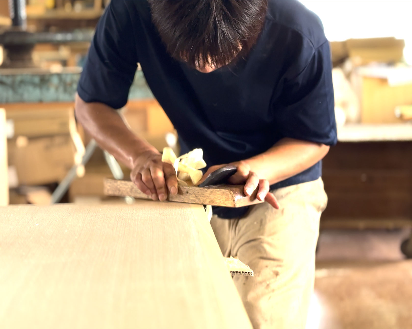 木工職人がかんなを使って木材を丁寧に削っている手元の様子