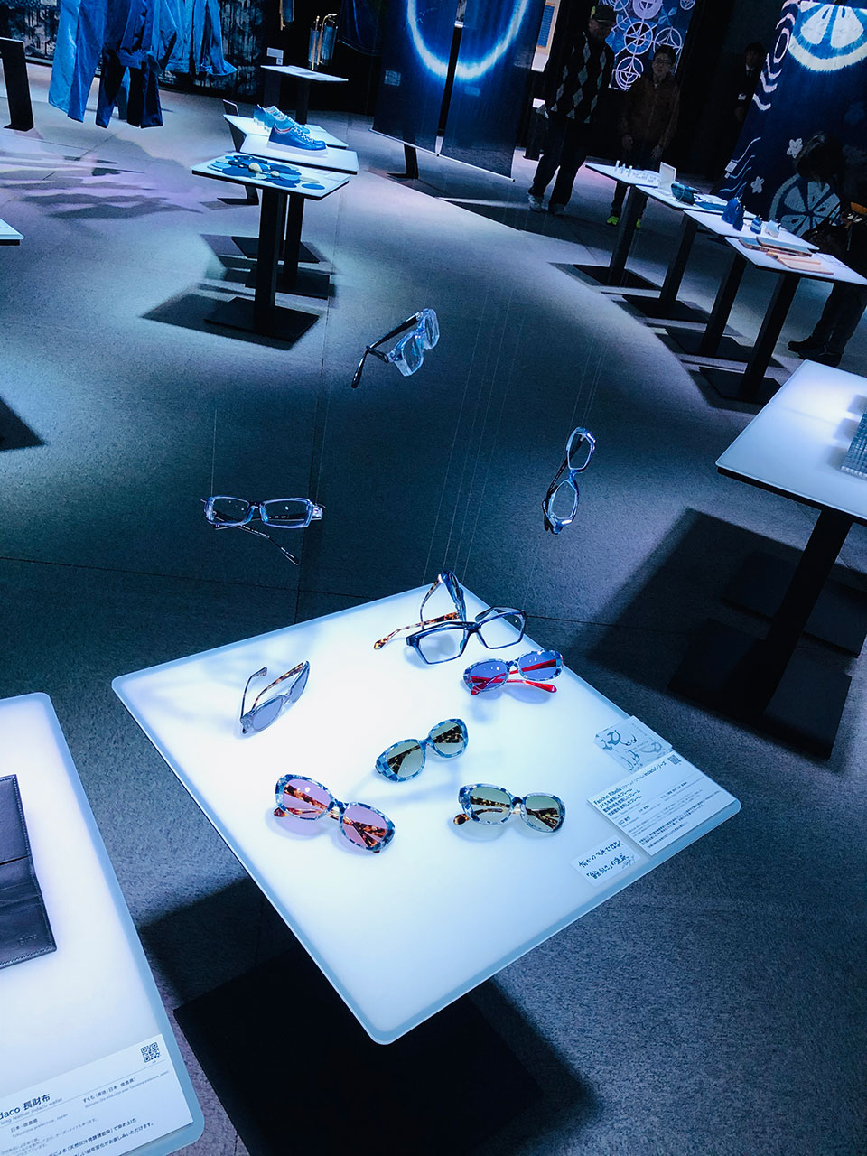 徳島の藍色を基調とした眼鏡フレーム展示、illuminated テーブルに並ぶ複数のサングラス