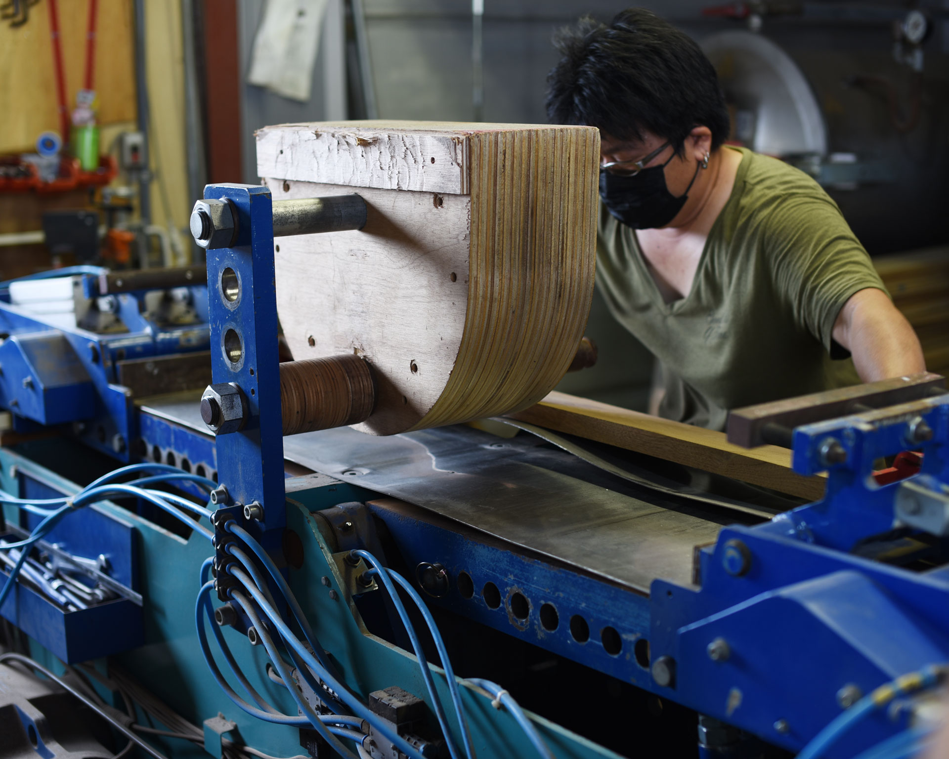 職人が曲木加工機でHARPチェアの背もたれ部分を成形している製造工程