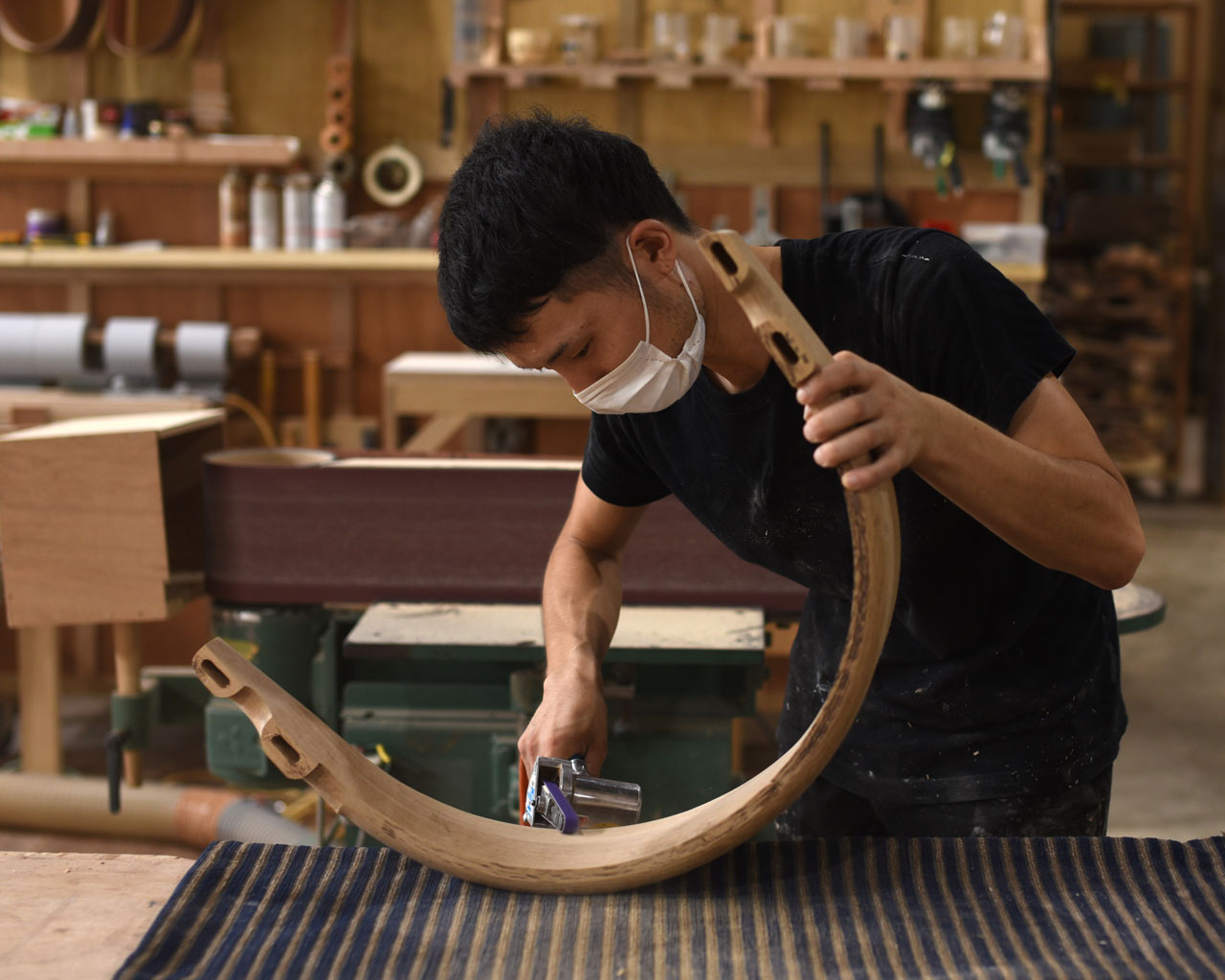 職人がHARPチェアの背もたれをやすりで丁寧に仕上げている手作業